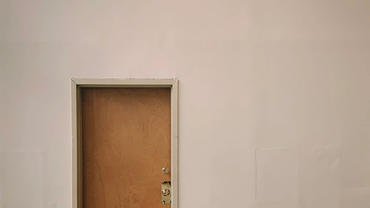A softly lit wooden door closed in a plain cream wall, holding the day’s noise on the other side - a Quiet Core Reset guide to The Beginner's Guide to Saying No: Start With One Small 'No'.
