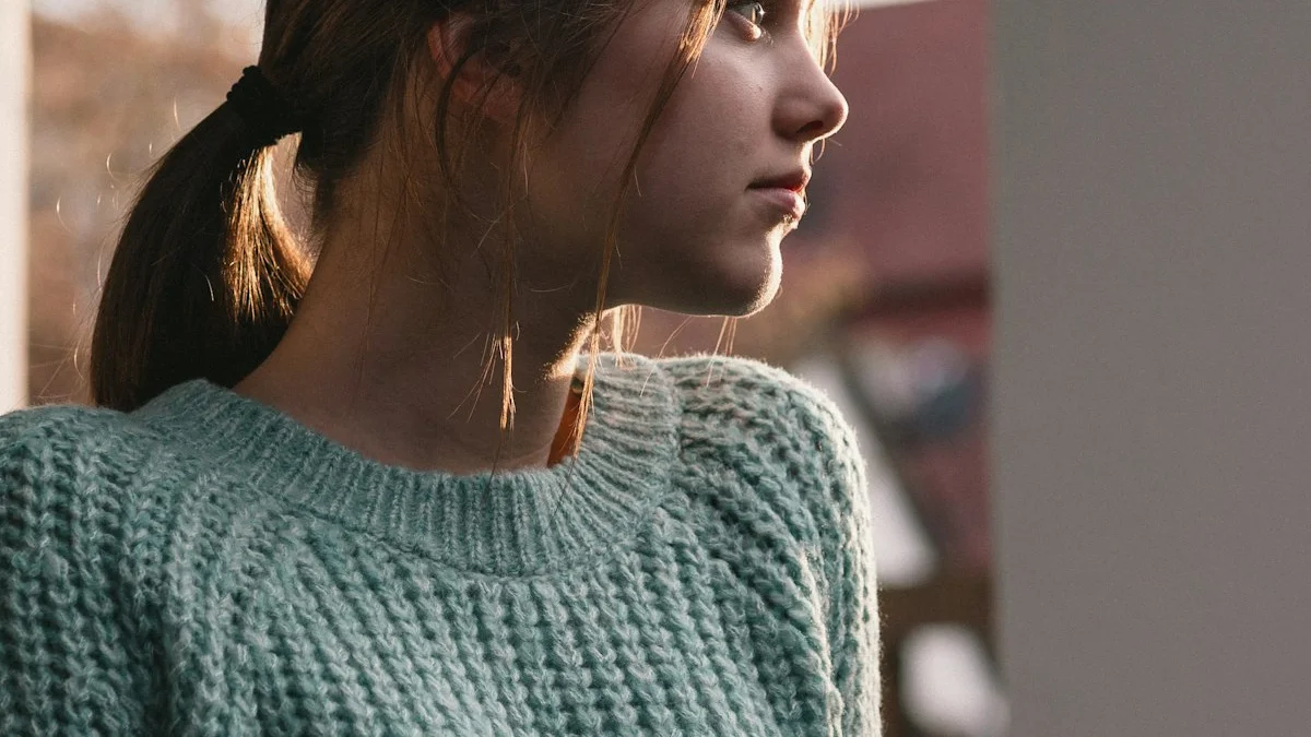 A woman in a sage knit sweater by a window, golden-hour light falling across her shoulder and neck - a Quiet Core Reset guide to The Body-Emotion Connection: Where Feelings Physically Live.