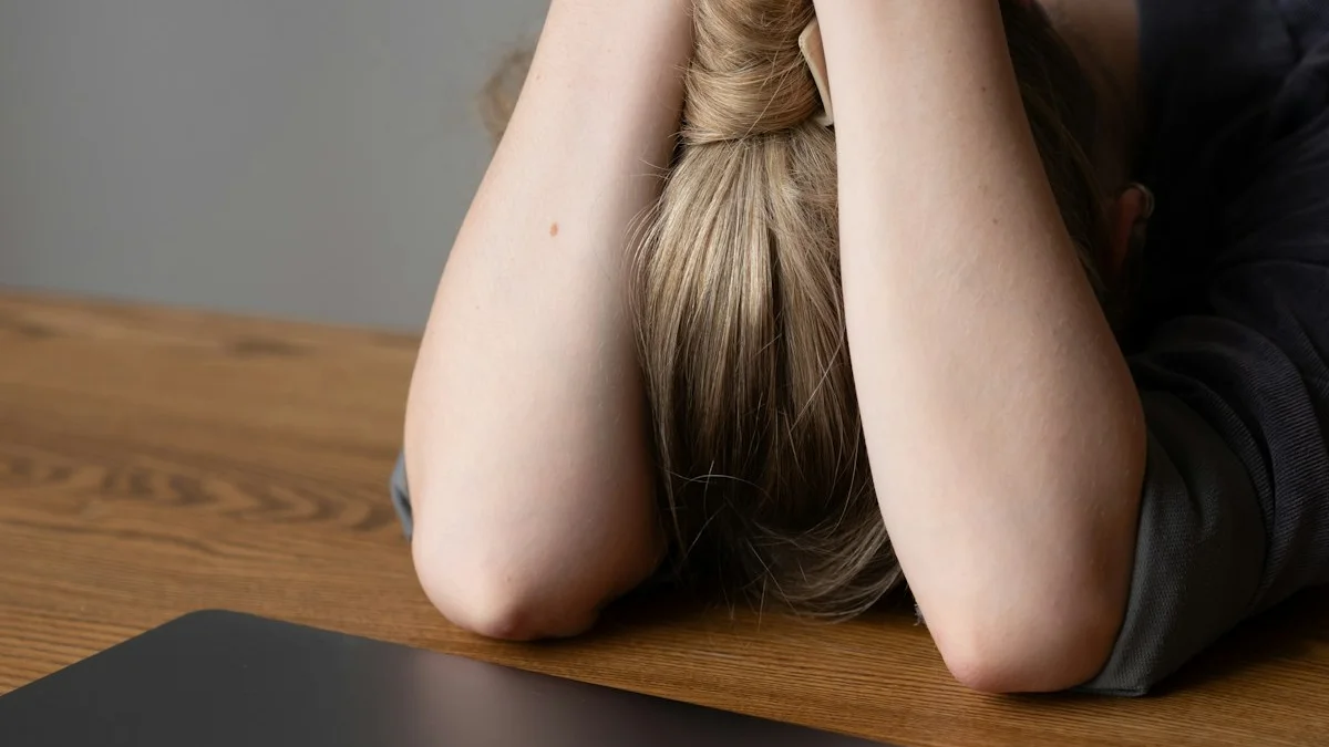 A person collapsed with their head in their arms on a wooden desk beside a closed laptop, drained by a scattered day - a Quiet Core Reset guide to Why Your Brain Feels Fried.