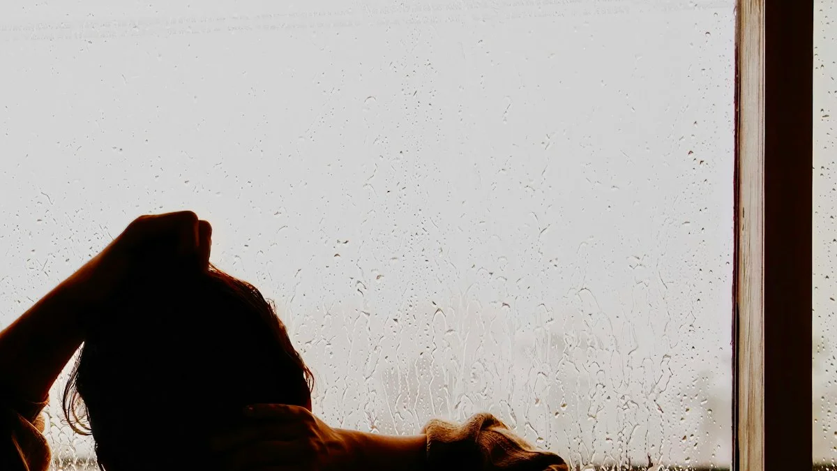 A woman seen from behind at a rain-streaked window, hand resting on her head in warm amber light - a Quiet Core Reset guide to Why You Compare Yourself to Others.