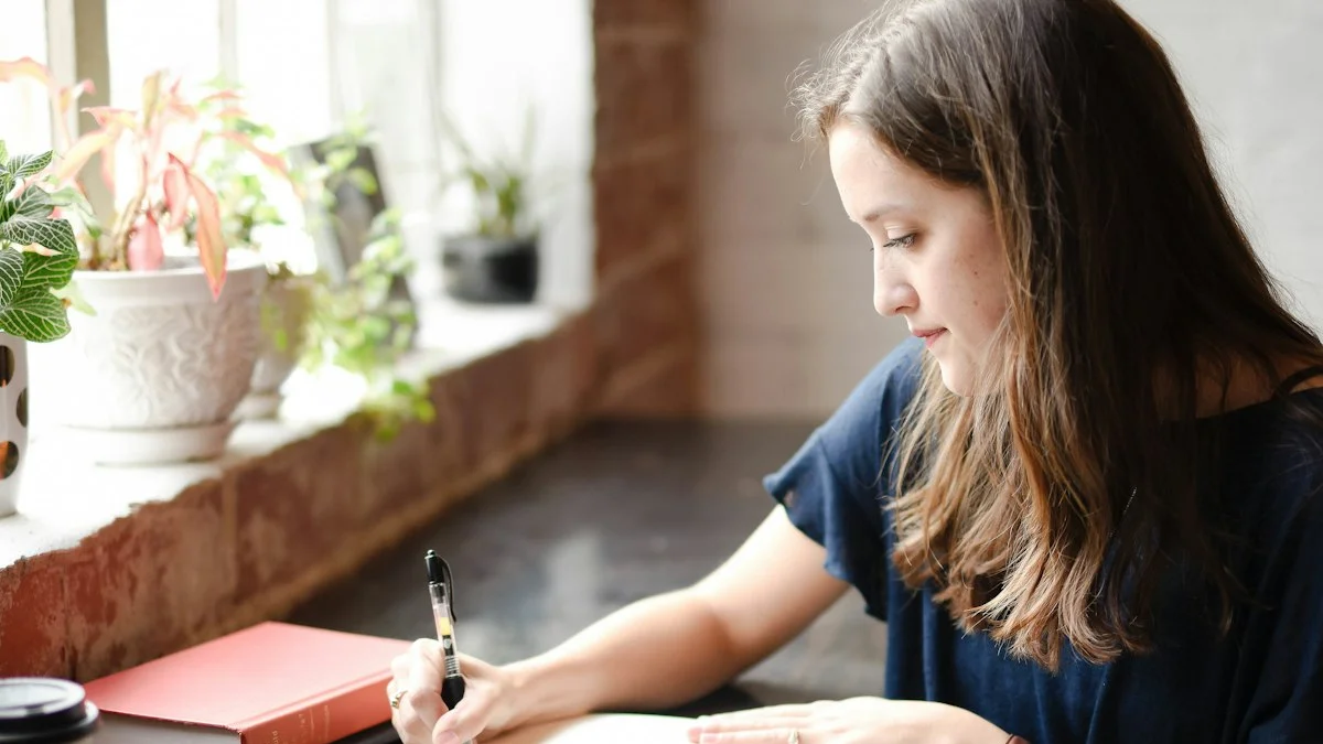 A woman writing in an open notebook at a sunlit window counter with plants and a coffee cup - a Quiet Core Reset guide to A 5-Minute Comparison Self-Check.
