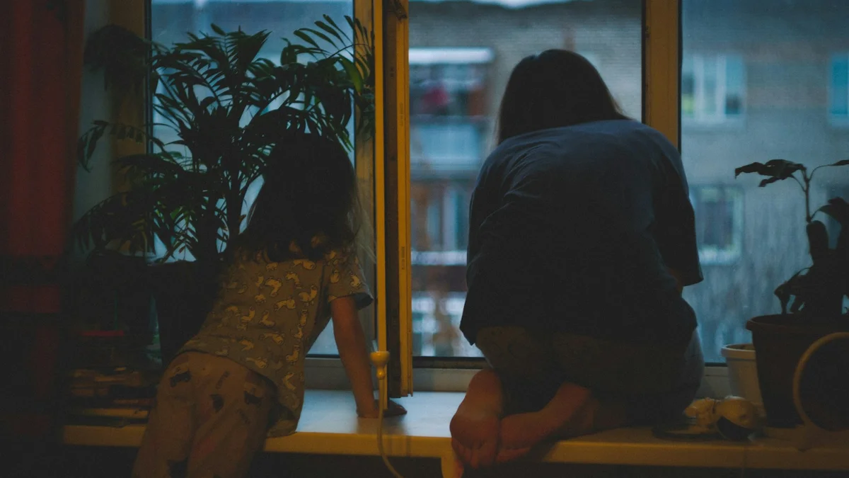 A mother and child watching the rain from a quiet window at dusk - a Quiet Core Reset guide to I Need 15 Minutes to Decompress.