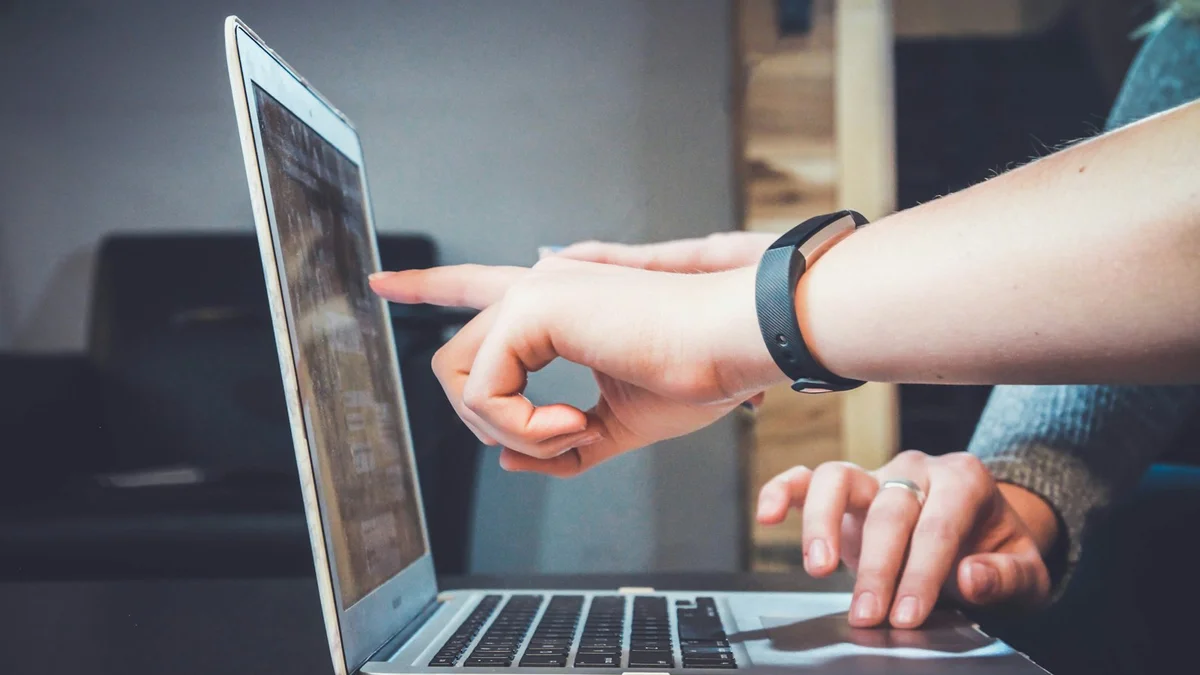 A person pointing at a laptop screen while another hand rests on the keyboard, a focused working moment - a Quiet Core Reset guide to Common Mistakes When Setting Digital Boundaries.