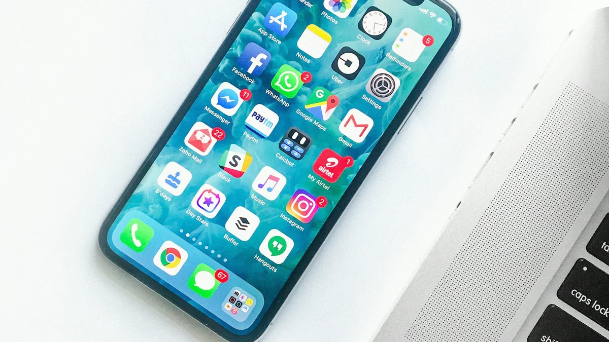 A close-up of a smartphone screen full of app icons and notifications next to a laptop keyboard - a Quiet Core Reset guide to Digital Overload.