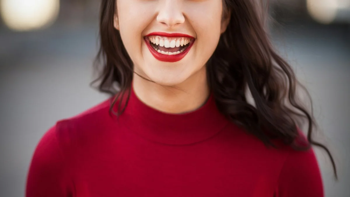 A smiling woman in a red turtleneck, joyful close-up portrait - a Quiet Core Reset guide to Why You Don't Have to Feel Ecstatic to Be Happy.