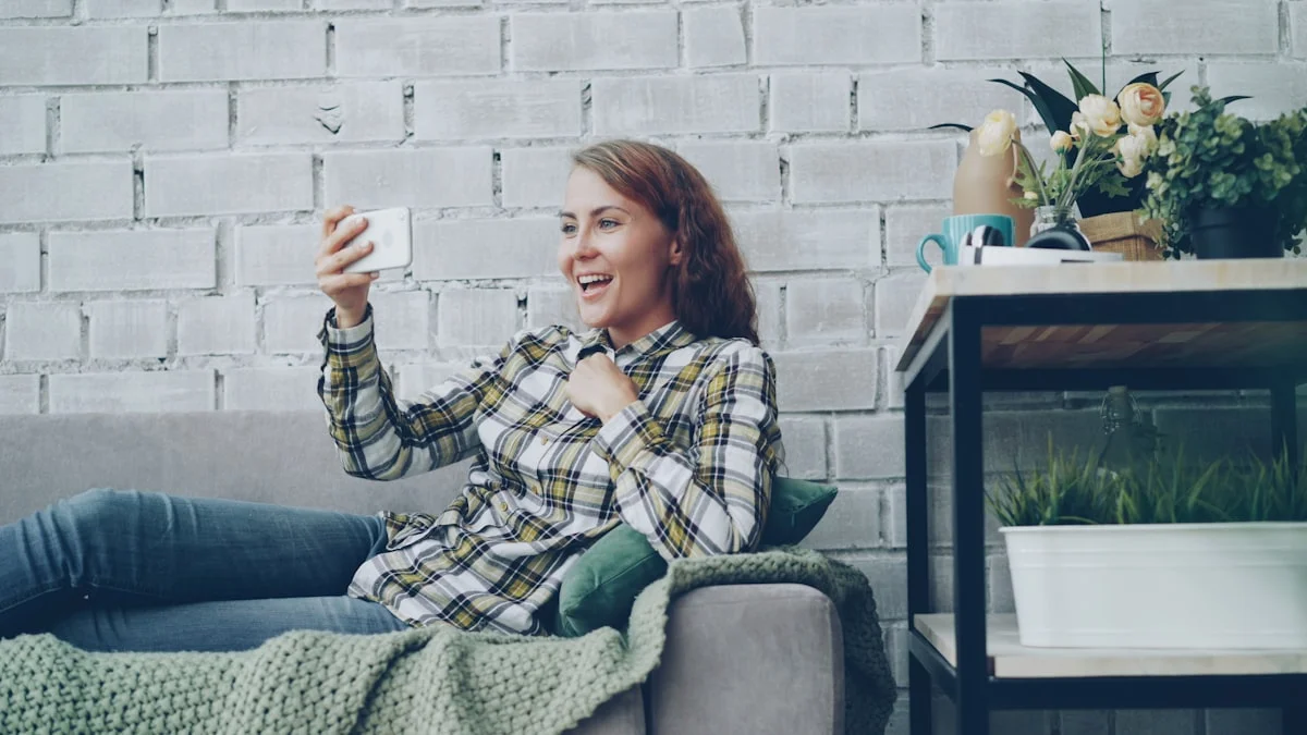 A woman smiling with relief during a video call on her couch, reaching out to the person who listens - a Quiet Core Reset guide to Emergency Contact Protocol.