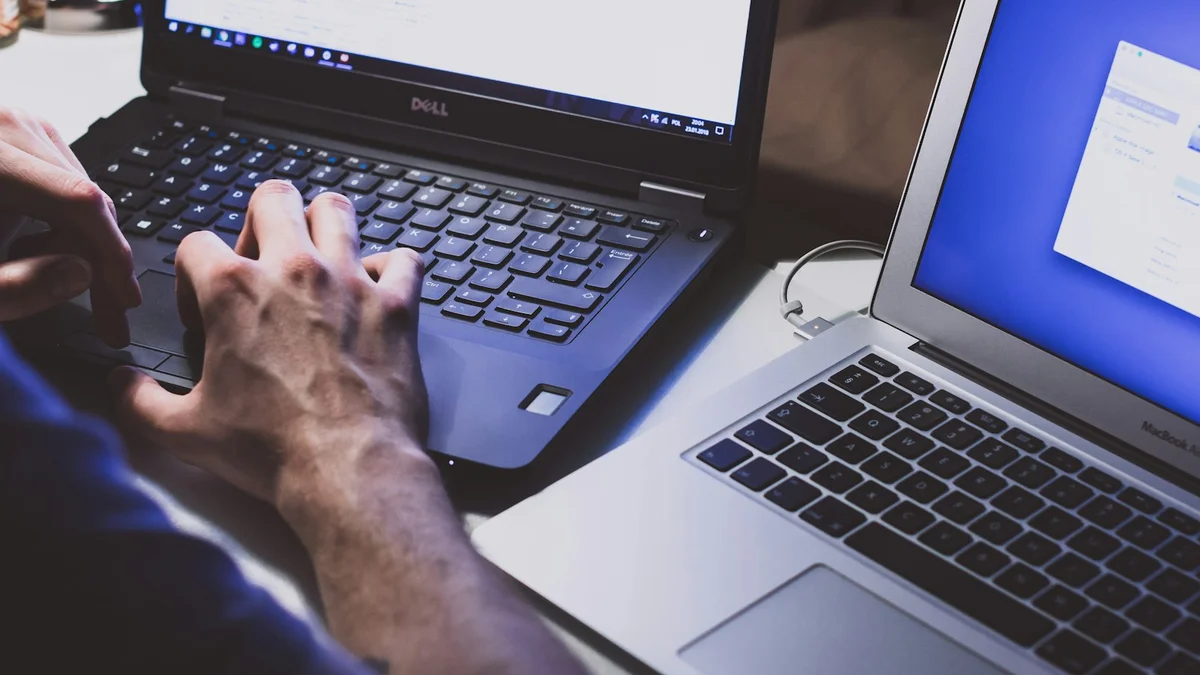 Two hands typing on a laptop keyboard beside a second open laptop, a late-night working scene - a Quiet Core Reset guide to Common Mistakes When Trying to Manage Your Energy.