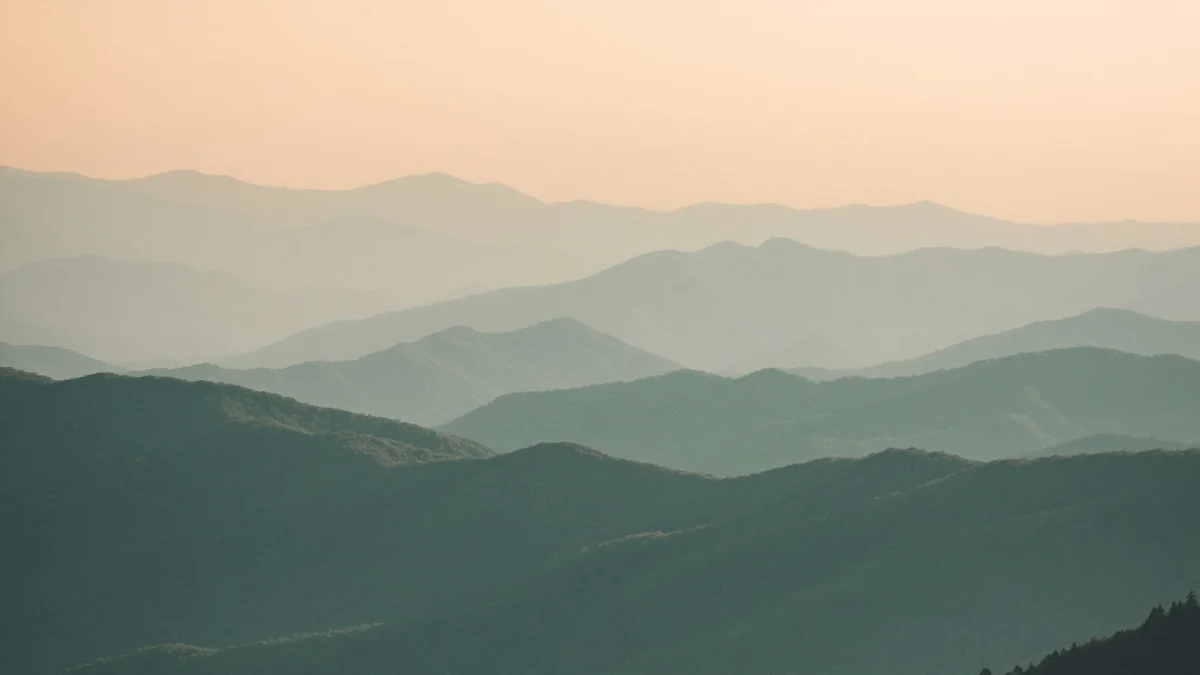 Layers of misty green mountains fading into a soft pale sky - a Quiet Core Reset guide to 1-10 Energy Scale.