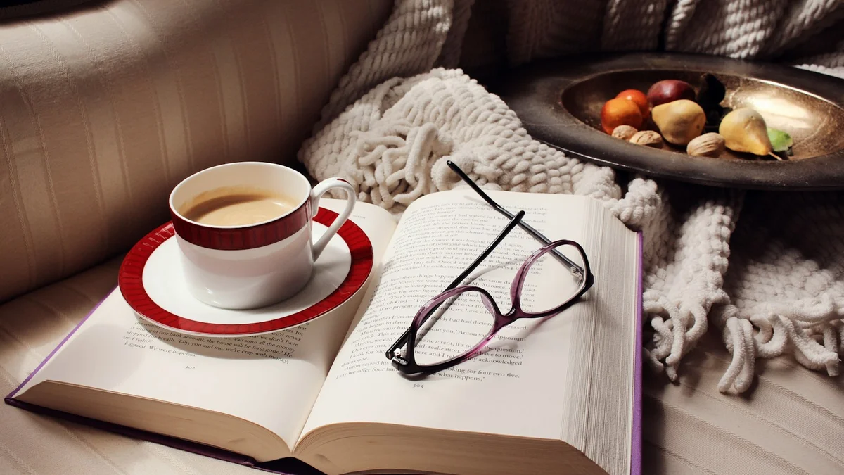 An open book with reading glasses and a cup of coffee on a cozy couch - a Quiet Core Reset guide to Family Energy.