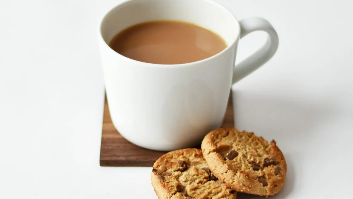 A white mug of milky coffee with two chocolate chip cookies on a wooden board - a Quiet Core Reset guide to How to Find Joy When You Have No Energy.