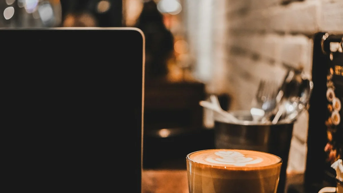 An open laptop and a glass of latte art side by side on a wooden cafe table in warm, dim light - a Quiet Core Reset guide to Are You Grinding or Living? A 3-Minute Honest Self-Check.