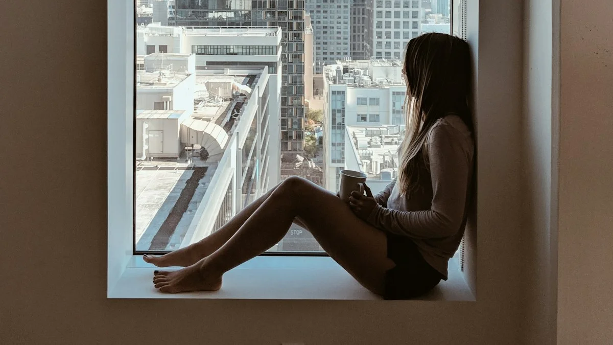 A woman with a mug sitting quietly on a wide window ledge, gazing out over the city - a Quiet Core Reset guide to Hidden Cost of Always Being Strong.