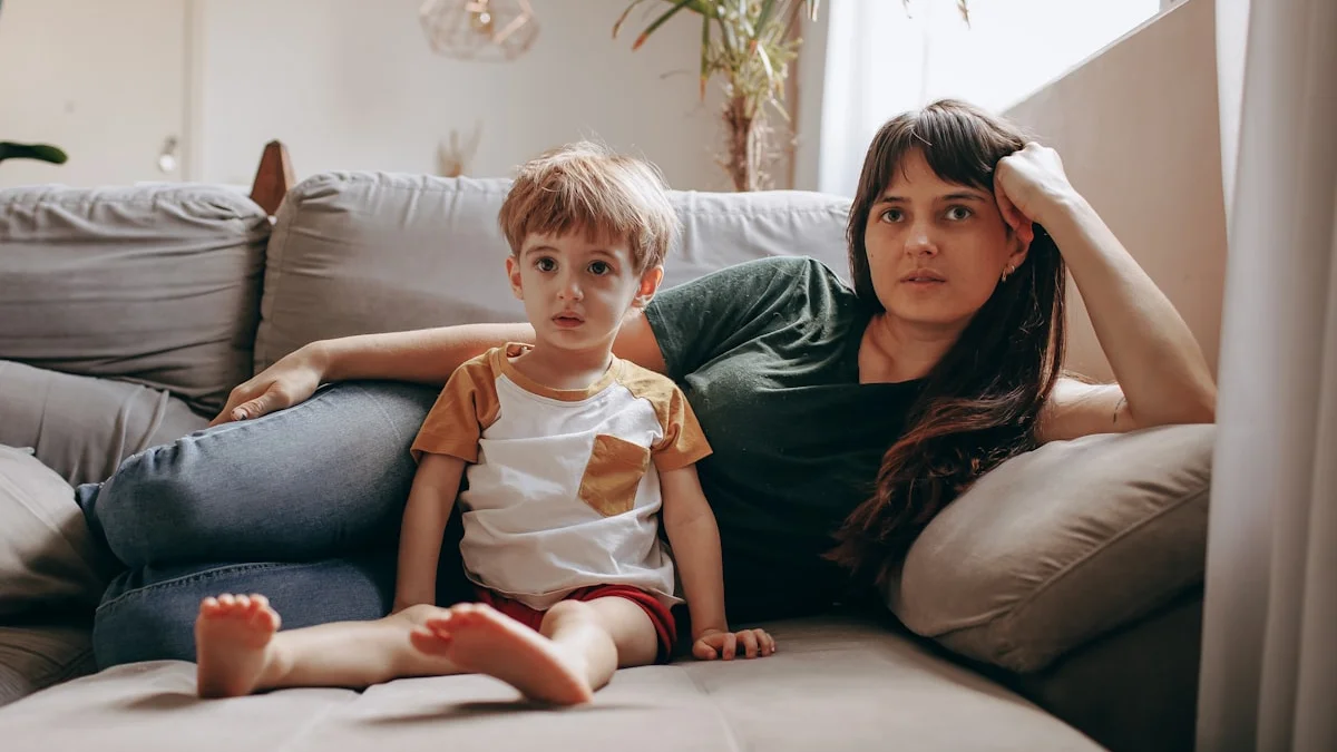 A weary mother leaning back on a sofa beside her young son, worn out from holding everything together - a Quiet Core Reset guide to High-Functioning Exhaustion for Parents.