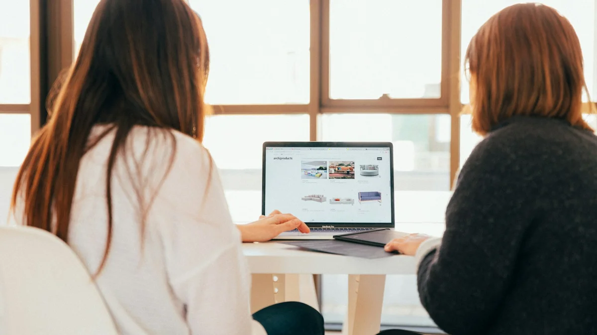 Two people sitting at a table looking at a laptop screen together - a Quiet Core Reset guide to How to Say No to Friends and Family Without Ruining Relationships.