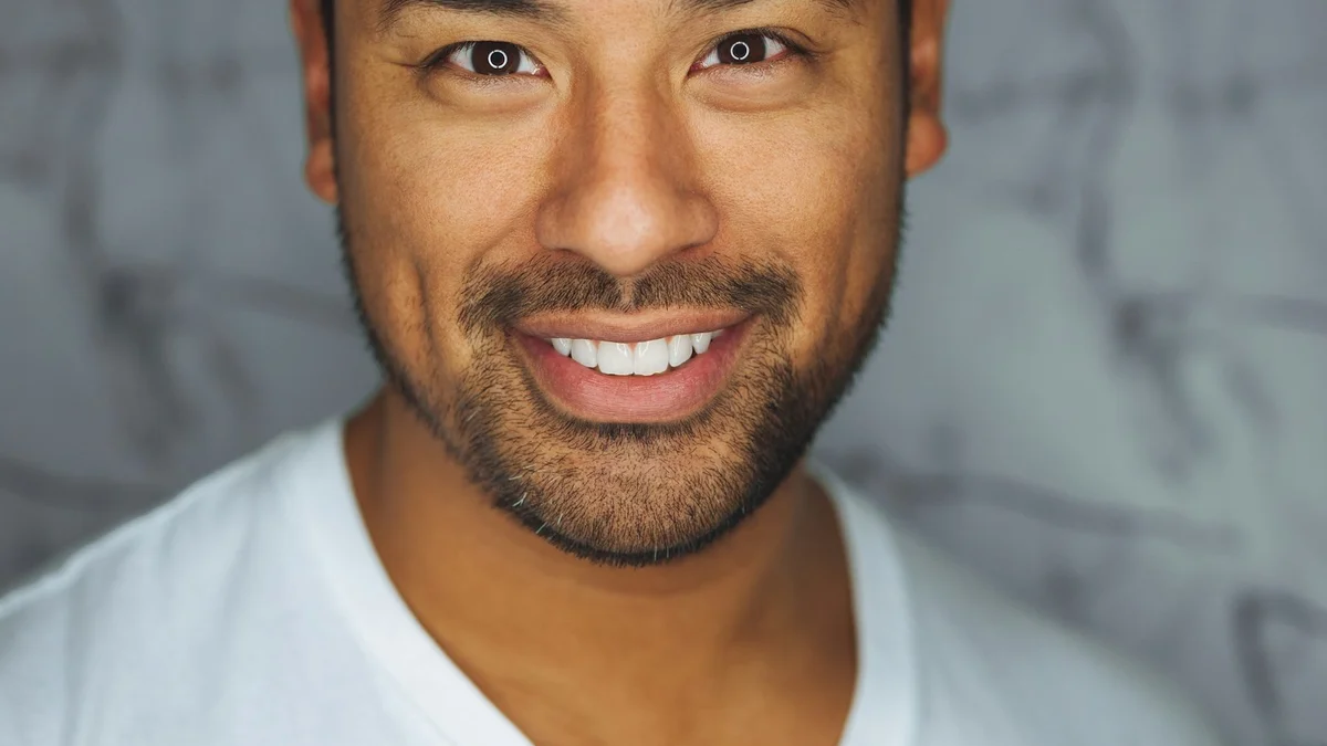 A close-up portrait of a smiling man with a beard wearing a white shirt - a Quiet Core Reset guide to How to Say No Without Feeling Like a Bad Person.