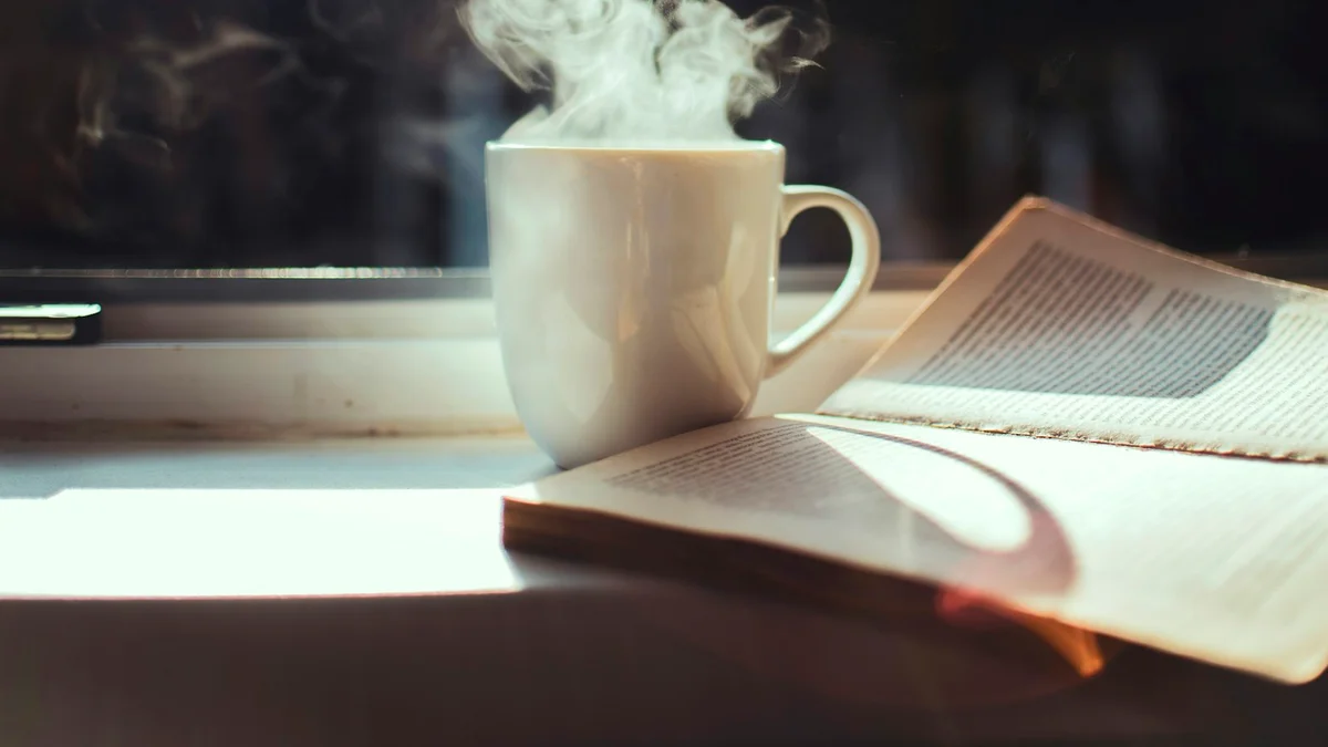 A warm mug steaming beside an open book on a quiet window sill in soft morning light - a Quiet Core Reset guide to the Inner Critic.