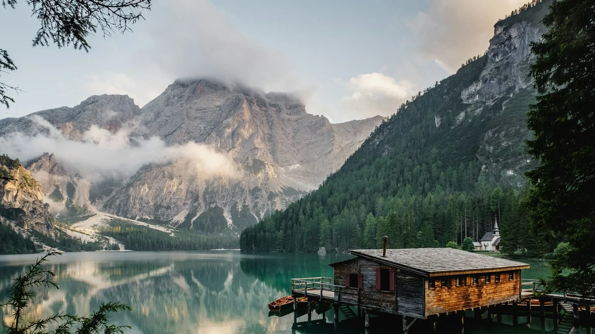 A wooden mountain cabin on a green lake with mist and peaks behind - a Quiet Core Reset guide to Why You're Living From the Neck Up.
