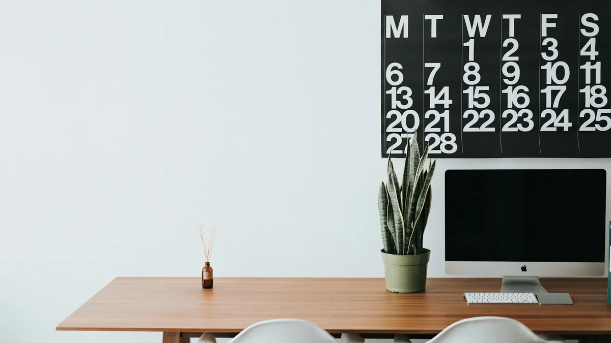 A tidy desk with a large calendar on the wall, a snake plant, a computer monitor and a wooden table - a Quiet Core Reset guide to How I Made Peace With My Phone.