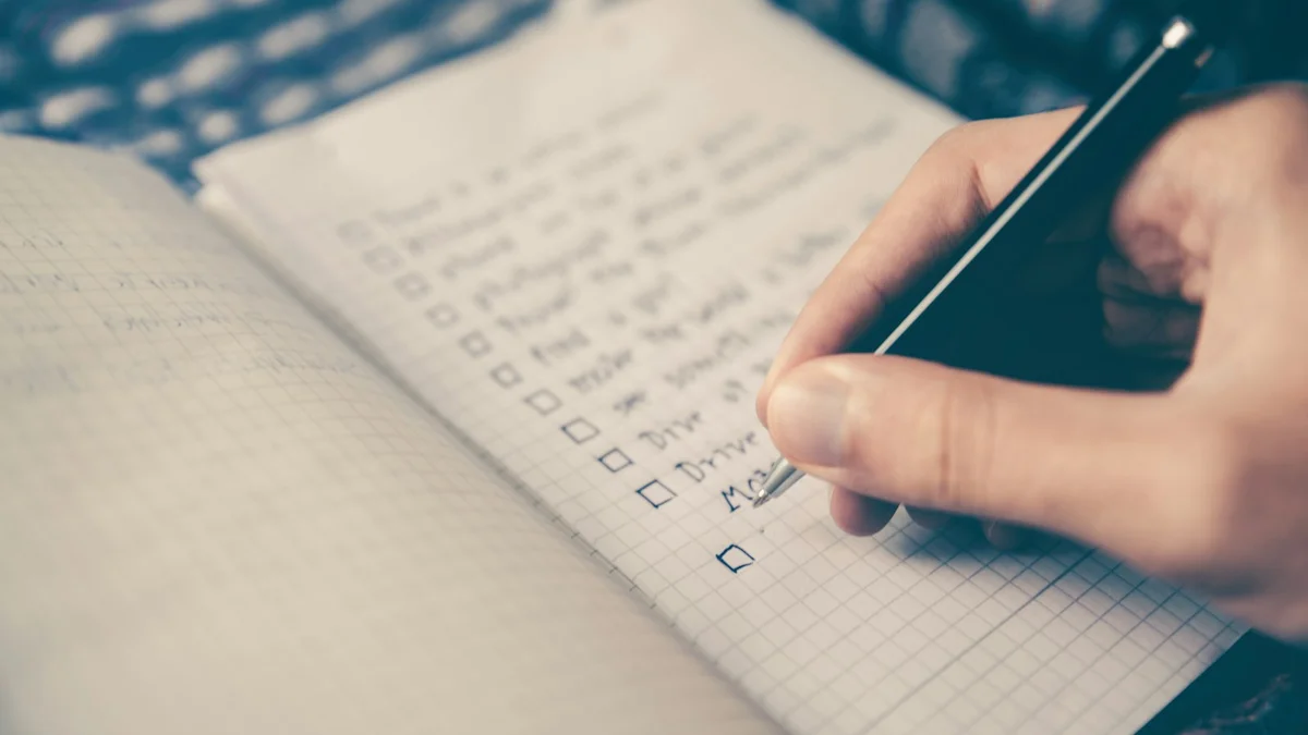A hand ticking items on a checklist in an open notebook, habit tracking - a Quiet Core Reset guide to How to Map Your Personal Energy Cycles in 7 Days.