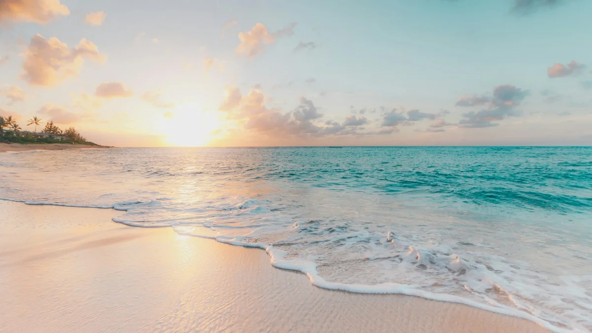 A peaceful turquoise beach at sunset with gentle waves and palm trees - a Quiet Core Reset guide to Micro-Resets vs. The Big Vacation.