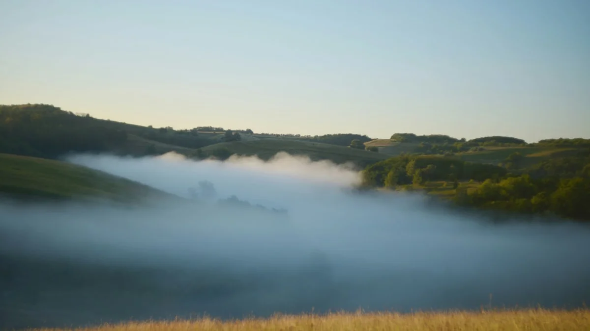 A bank of morning fog pooling in one valley below rolling hills and clear sky, one grey patch coloring the whole scene - a Quiet Core Reset guide to Overgeneralization: When One Bad Day Means Everything Is Bad.