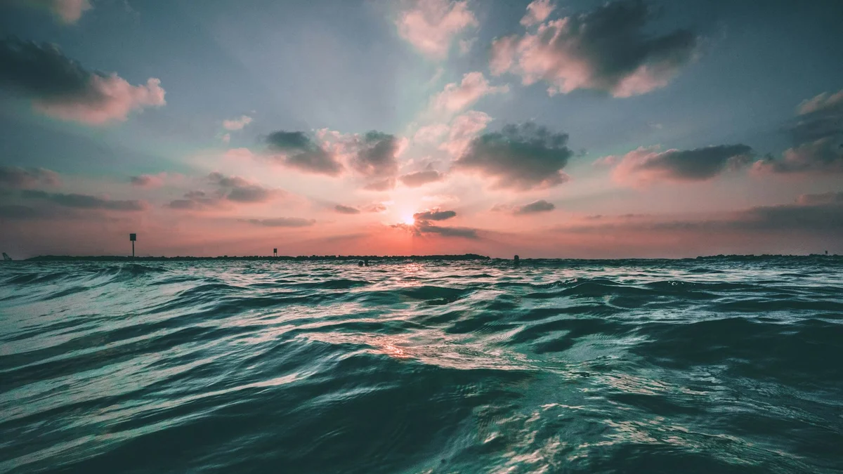 Rolling dark ocean waves under a dramatic pink sunset sky - a Quiet Core Reset guide to Your Personal Energy Rhythm.