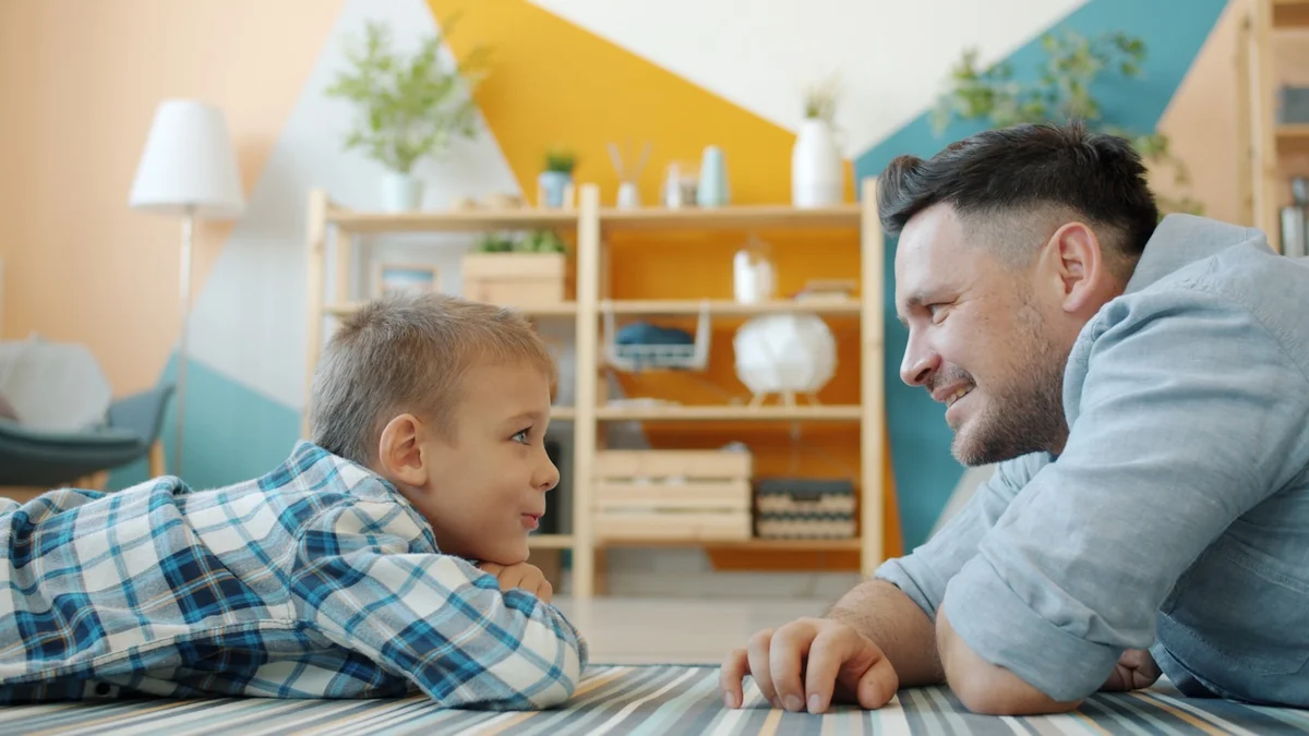 A father and son lying face to face on the floor at home - a Quiet Core Reset guide to How to Play With Your Kids When You're Exhausted (It Counts).
