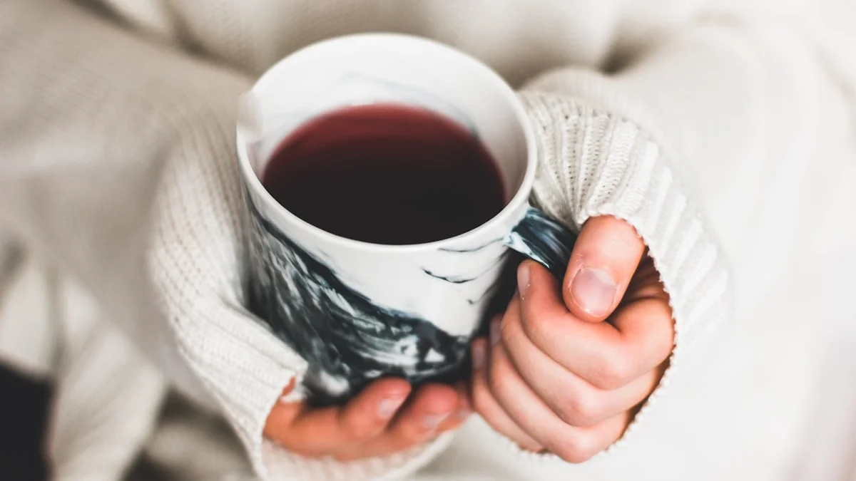 Hands in a cream sweater wrapped around a warm mug of tea, a small pause - a Quiet Core Reset guide to How to Process Emotions When You Have No Time or Energy.