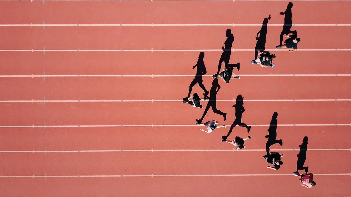 An aerial view of runners in silhouette on a red running track - a Quiet Core Reset guide to Why 'Just Push Through' Fails When Your Energy Is Empty.