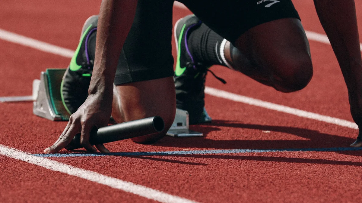 A sprinter crouched in a starting block on a red track, ready to run - a Quiet Core Reset guide to Why Just Push Through Keeps You Out of Rest & Digest.