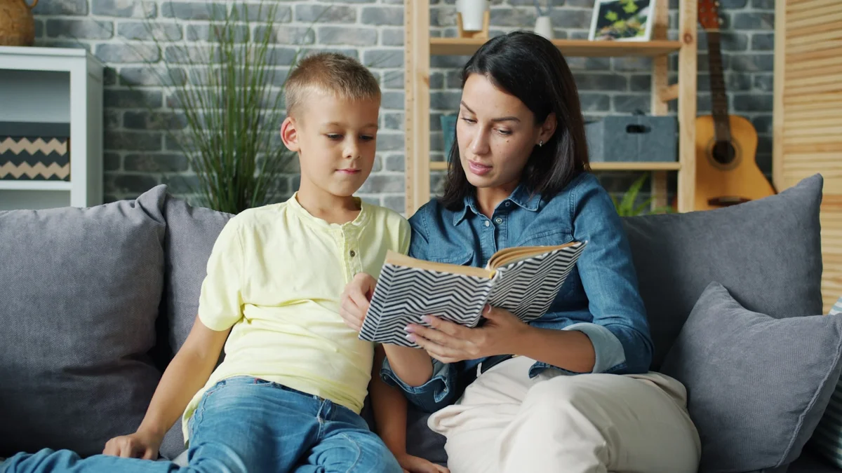 A mother reading a book with her son on the couch - a Quiet Core Reset guide to Quality Time vs. Quantity Time.