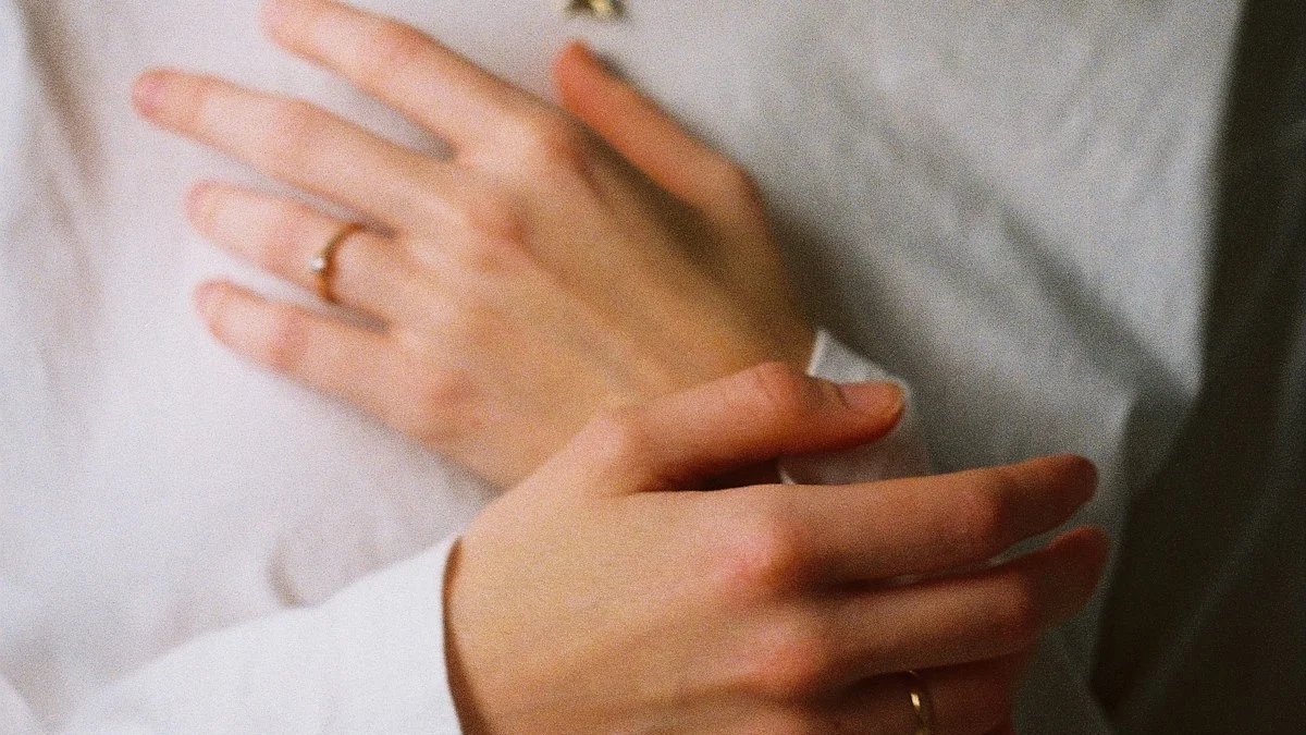 Two hands resting gently over the heart on a soft white shirt, a hand-on-chest breathing pause - a Quiet Core Reset guide to How to Regulate Your Nervous System in 10 Minutes.