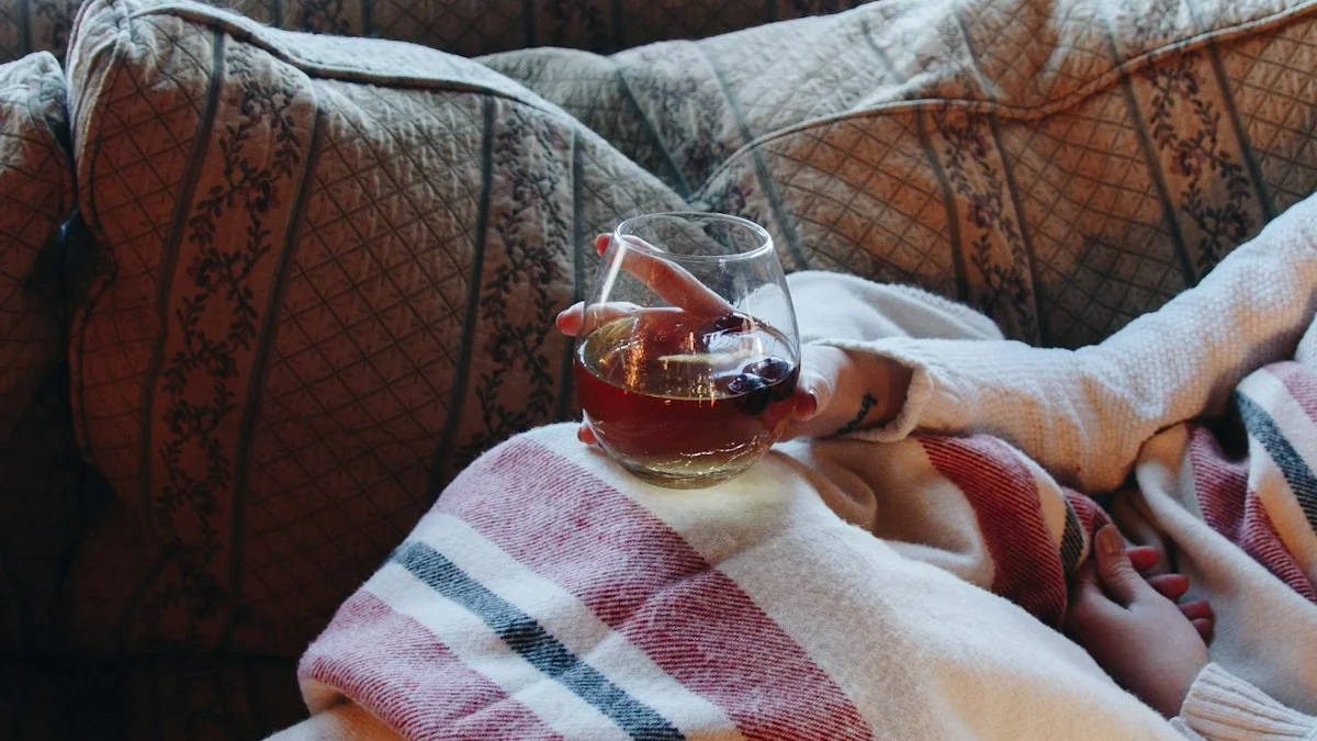 A person rests under a striped blanket on a vintage sofa, cradling a warm drink by a winter window - a Quiet Core Reset guide to Regulating Your Nervous System When You're Already Burned Out.