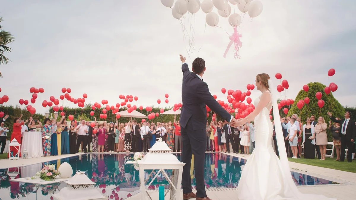 A wedding scene with a bride and groom releasing red ballons by a pool, a crowd of guests - a Quiet Core Reset guide to Rest & Digest for High Performers.