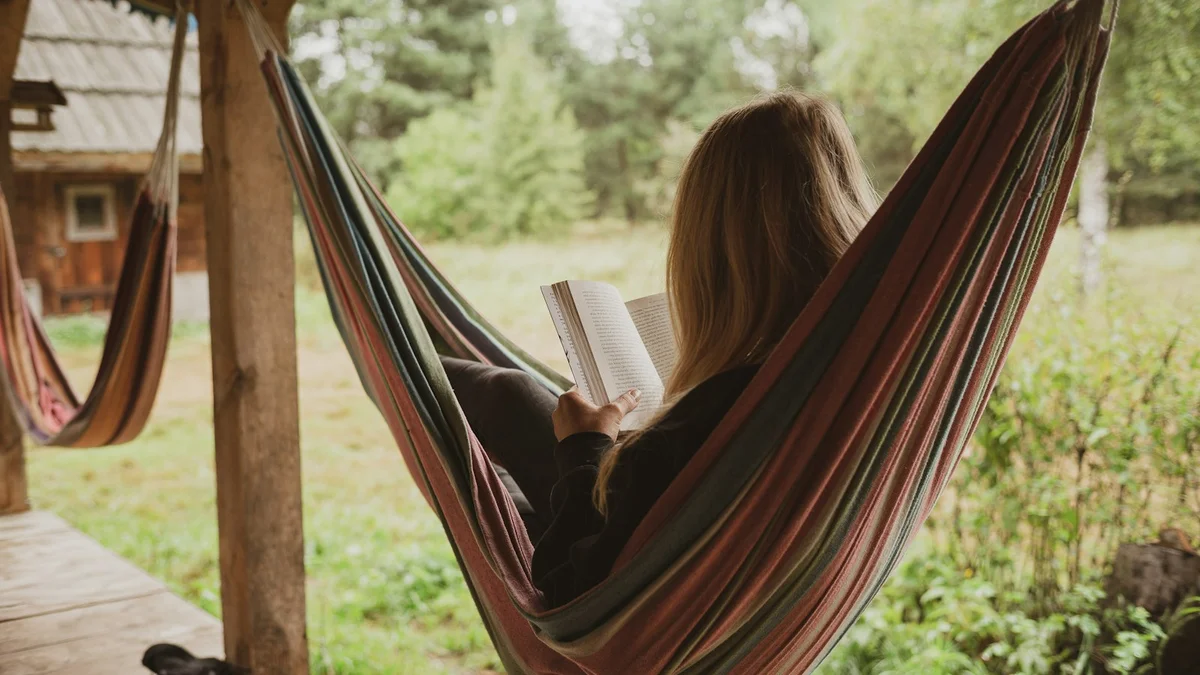 A woman reading a book in a striped hammock on a wooden porch - a Quiet Core Reset guide to Rest Guilt Explained Simply.
