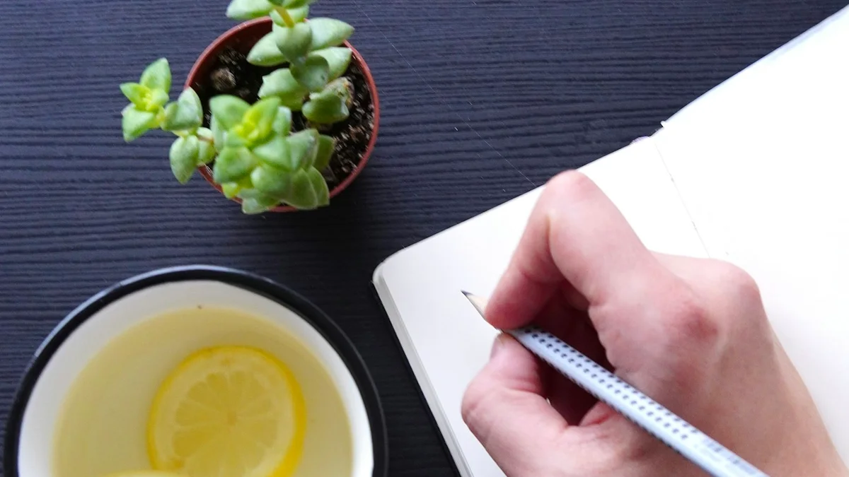 A hand writing in an open notebook beside a mug of lemon water - a Quiet Core Reset guide to Rest Guilt Self-Check.