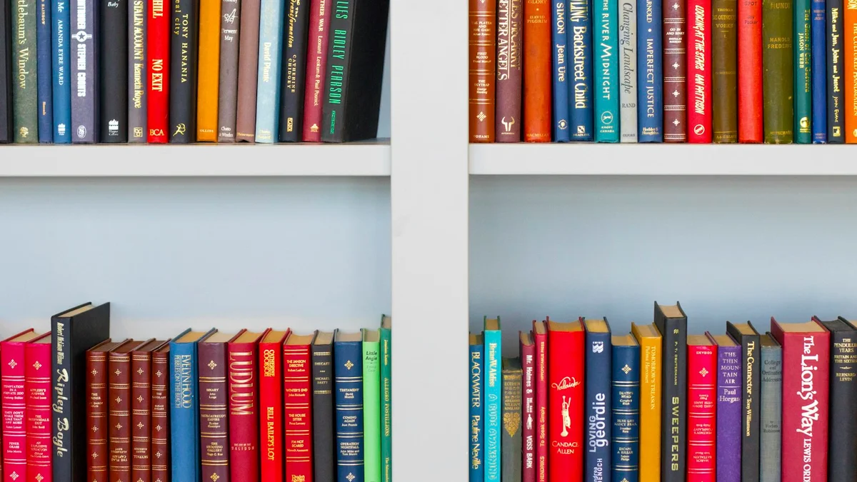 Colorful book spines on white shelves, a tidy bookshelf - a Quiet Core Reset guide to Rest Is Not a Reward.