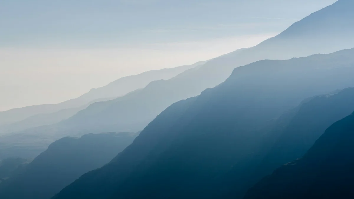 Layers of blue mountains fading into mist, soft and atmospheric - a Quiet Core Reset guide to Designing a Routine for Your Lowest-Energy Days.