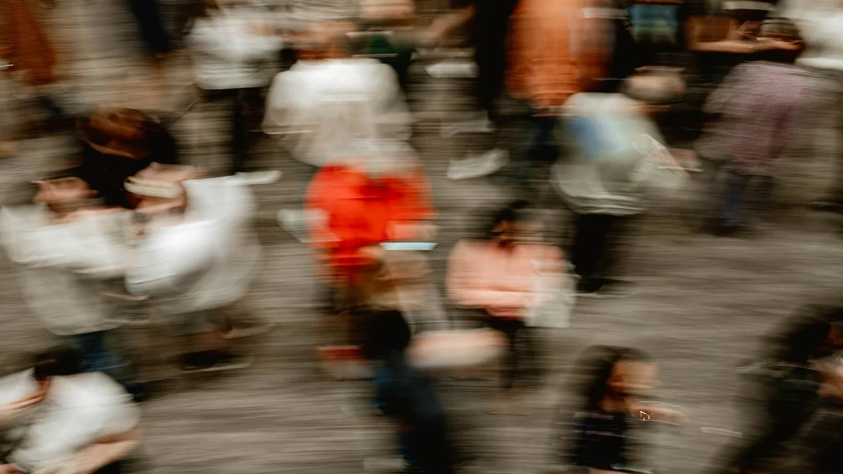 A motion-blurred crowd of commuters rushing across a busy concourse - a Quiet Core Reset guide to 8 Signs You're Rushing Through a Life You Don't Need to Rush.