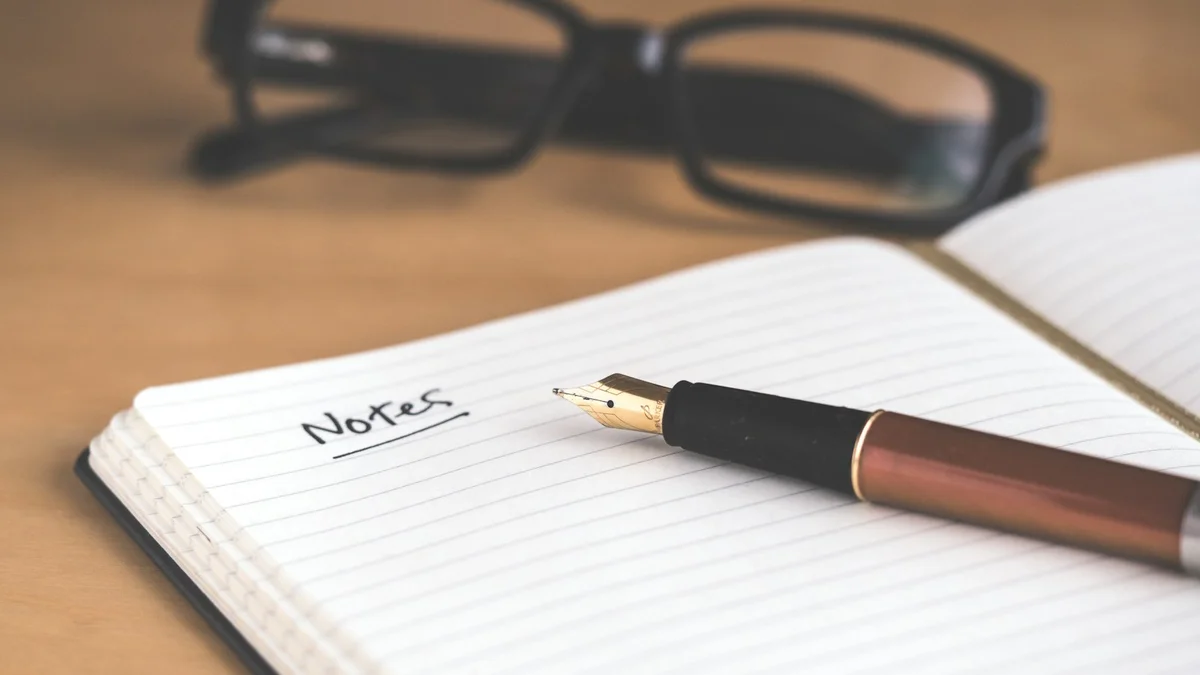 An open notebook with a pen and glasses resting on a wooden desk - a Quiet Core Reset guide to A 3-Minute Sleep Recovery Self-Check (No Wearable Required).
