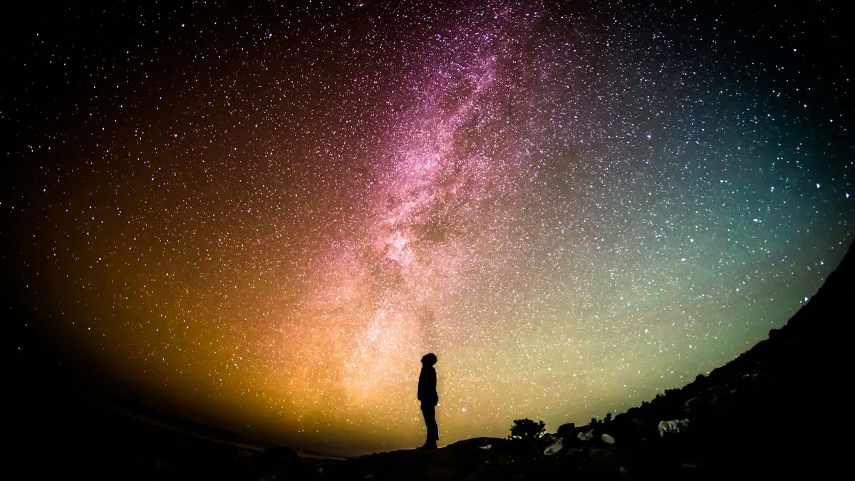 A person gazing up at a starry night sky - a Quiet Core Reset guide to Sleep Recovery for Shift Workers.