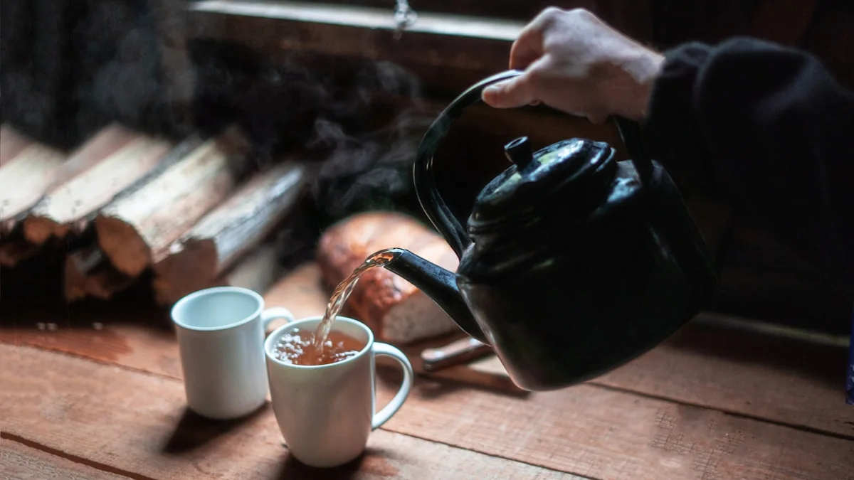 Hot water poured from a black kettle into a ceramic mug on a rustic wooden table - a Quiet Core Reset guide to living slower.