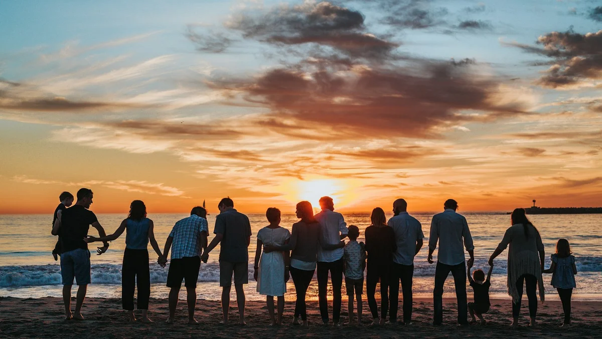 A large group of people standing on a beach watching a sunset, a family gathering in silhouette - a Quiet Core Reset guide to How Small Joys Rebuild Trust in Life.