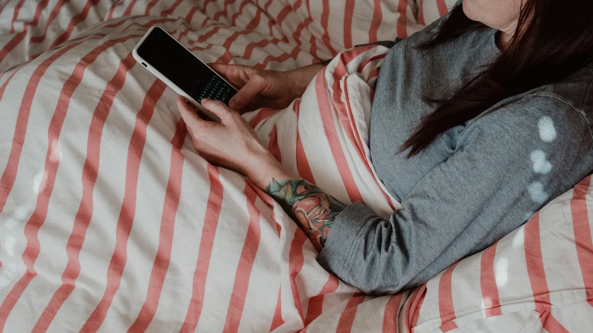 A person lying under a striped duvet answering messages on a phone in low evening light, a reflex no one notices - a Quiet Core Reset guide to Subtle Signs Your Boundaries Are Eroding.