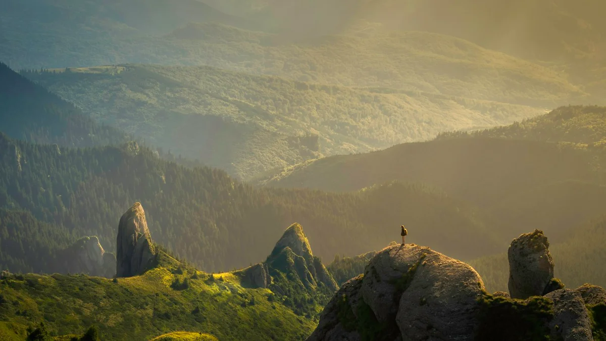 A lone figure standing on a rocky peak overlooking a vast sunlit mountain valley - a Quiet Core Reset guide to Subtle Signs Burnout Recovery Is Working.