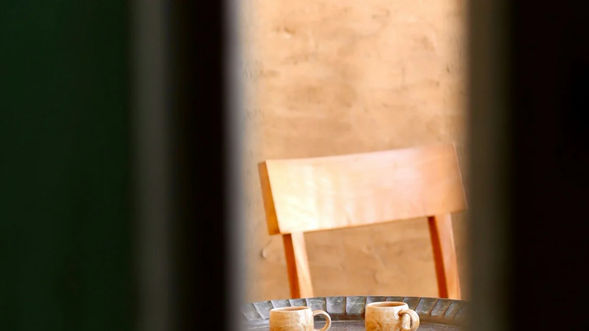 Two mugs waiting on a small wooden table beside a chair - a Quiet Core Reset guide to How to Talk to Yourself Like a Friend.