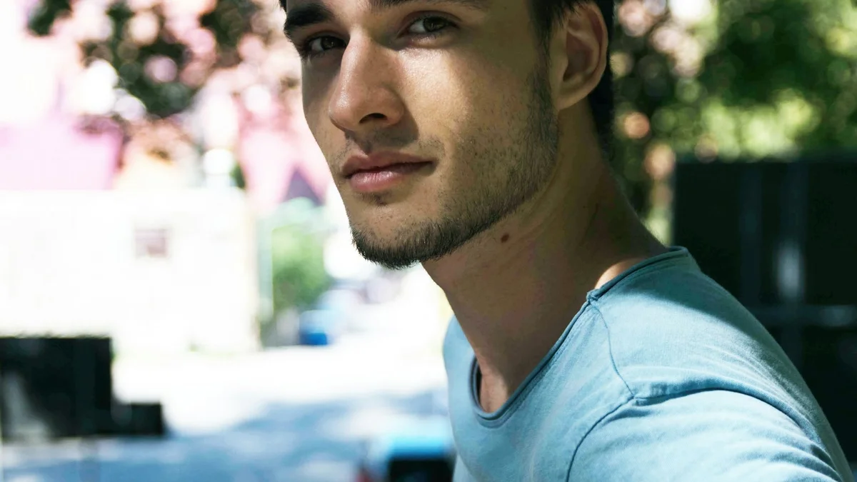A close-up portrait of a young man with a beard looking off-camera in natural light - a Quiet Core Reset guide to Science Behind 90-Minute Work Blocks.