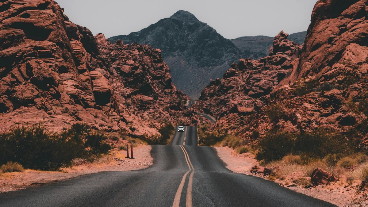 An empty road winding through red rock desert canyons toward a distant peak - a Quiet Core Reset guide to Why You Don't Notice You're Tense Until It Hurts.