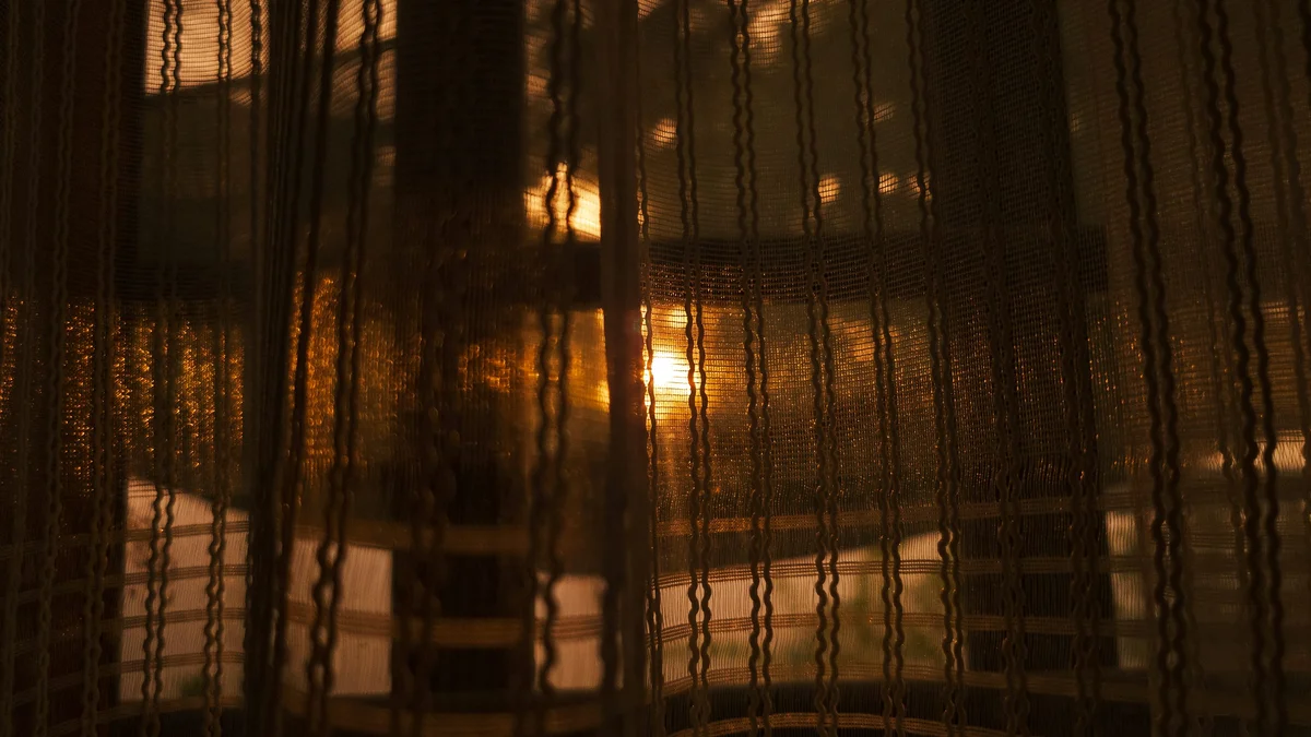 Warm golden light glowing through sheer curtains in a dim room - a Quiet Core Reset guide to Waking Up Tired After 8 Hours.
