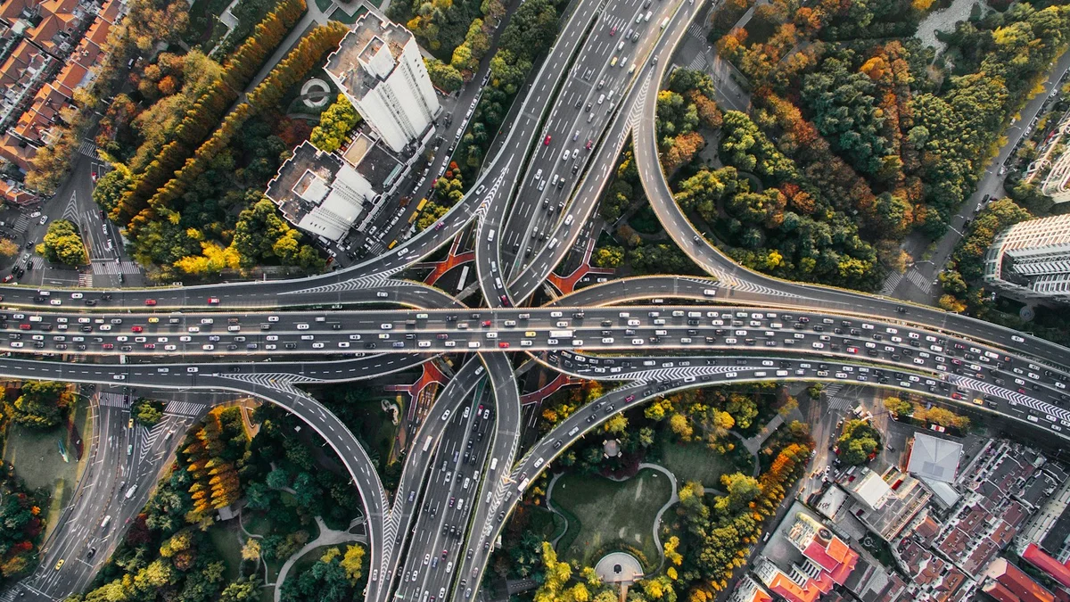 An aerial view of a complex multi-lane highway interchange surrounded by autumn trees and buildings - a Quiet Core Reset guide to Walking Without Purpose.